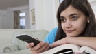 person watches television with remote control and book