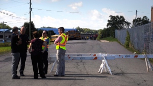 School staff talks with the police while students wait to board buses during evacuation procedures at Charlottetown Rural High School in Charlottetown, P.E.I., on Wednesday, September 21, 2016. RCMP say someone faxed a bomb threat against schools on Prince Edward Island this morning. THE CANADIAN PRESS/Nathan Rochford