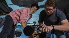 Jeongwan Jin and Chris Pugh of the University of Waterloo's Institute for Quantum Computing install a telescope in a National Research Council operated aircraft. The telescope was used to detect a laser beam transmitted from the ground that carries a coded message. Researchers hope to the deploy the technology on a future satellite that would be capable of sending secure information across the globe. (National Research Council)
